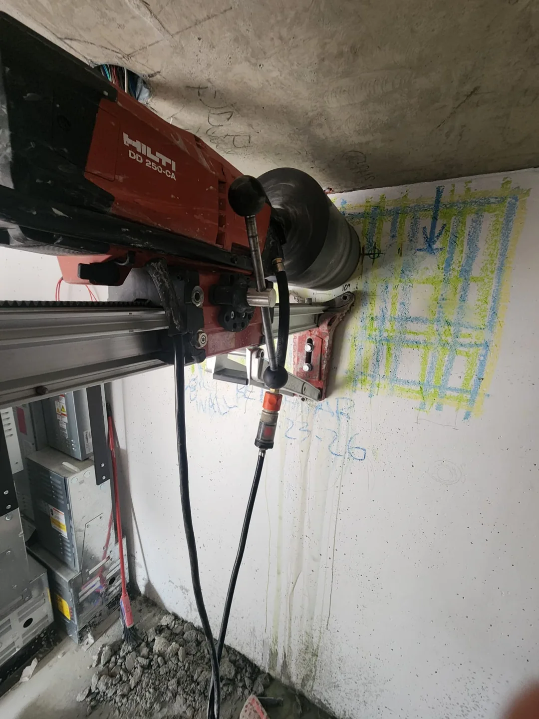 Core drilling rig positioned against a concrete wall