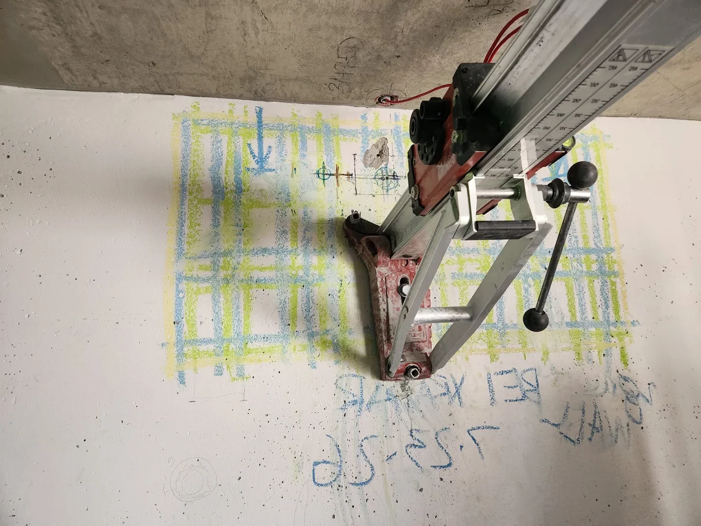 Wall-mounted core drilling equipment beside scan markings on concrete