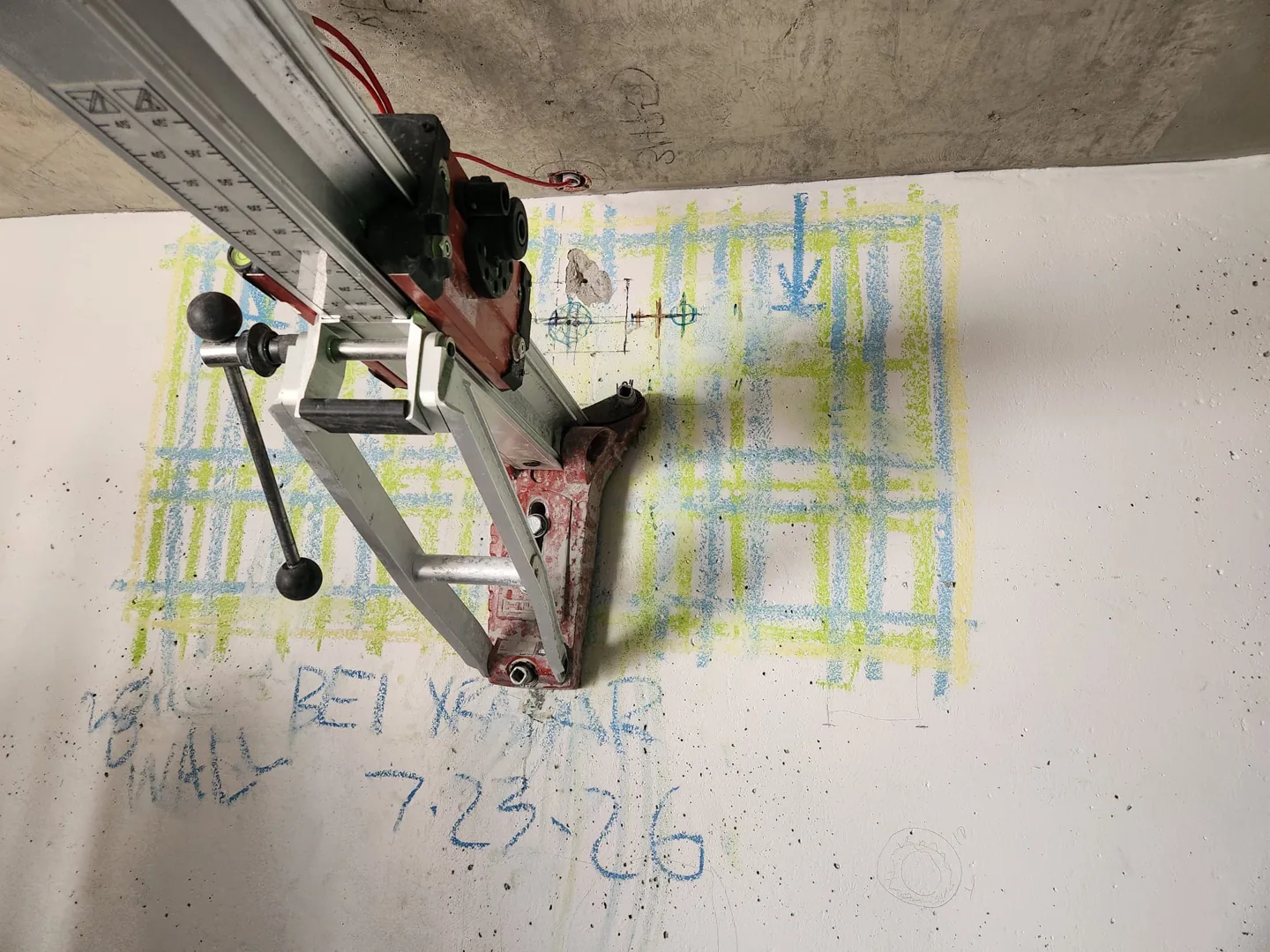 Core drilling equipment positioned against a marked concrete wall