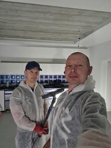 Two workers on site beneath a concrete-look ceiling