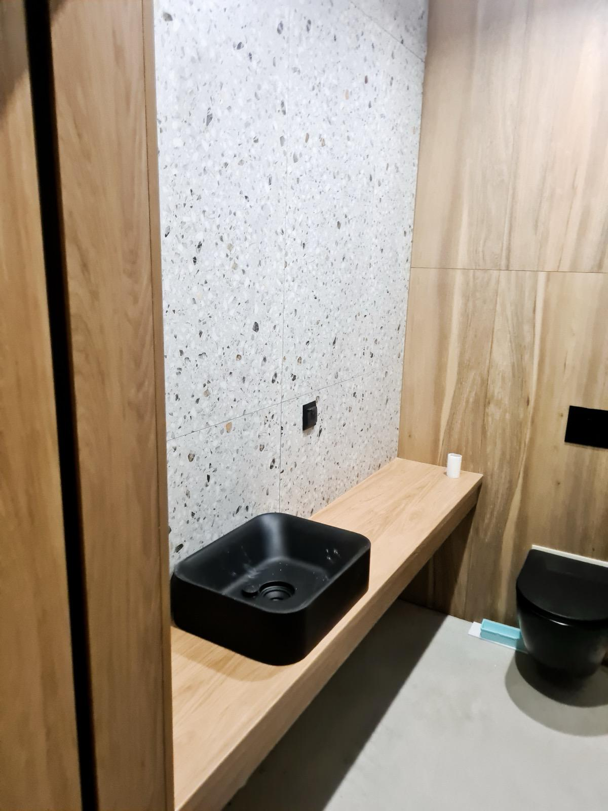 Bathroom with terrazzo tile, wood-look finishes and a black vessel sink