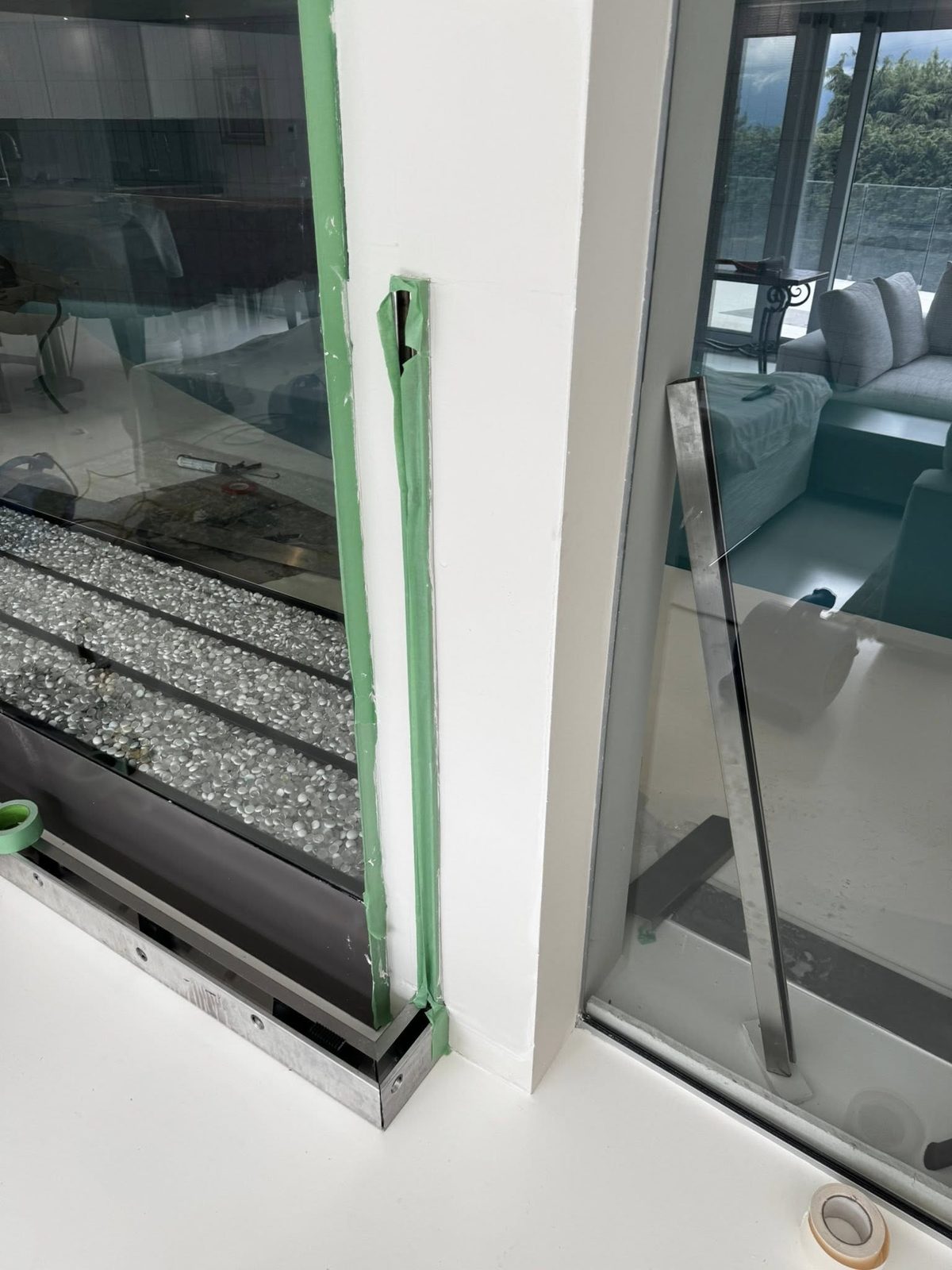 Detailed caulking and finishing work around glass partition during estate preparation in Jericho Beach