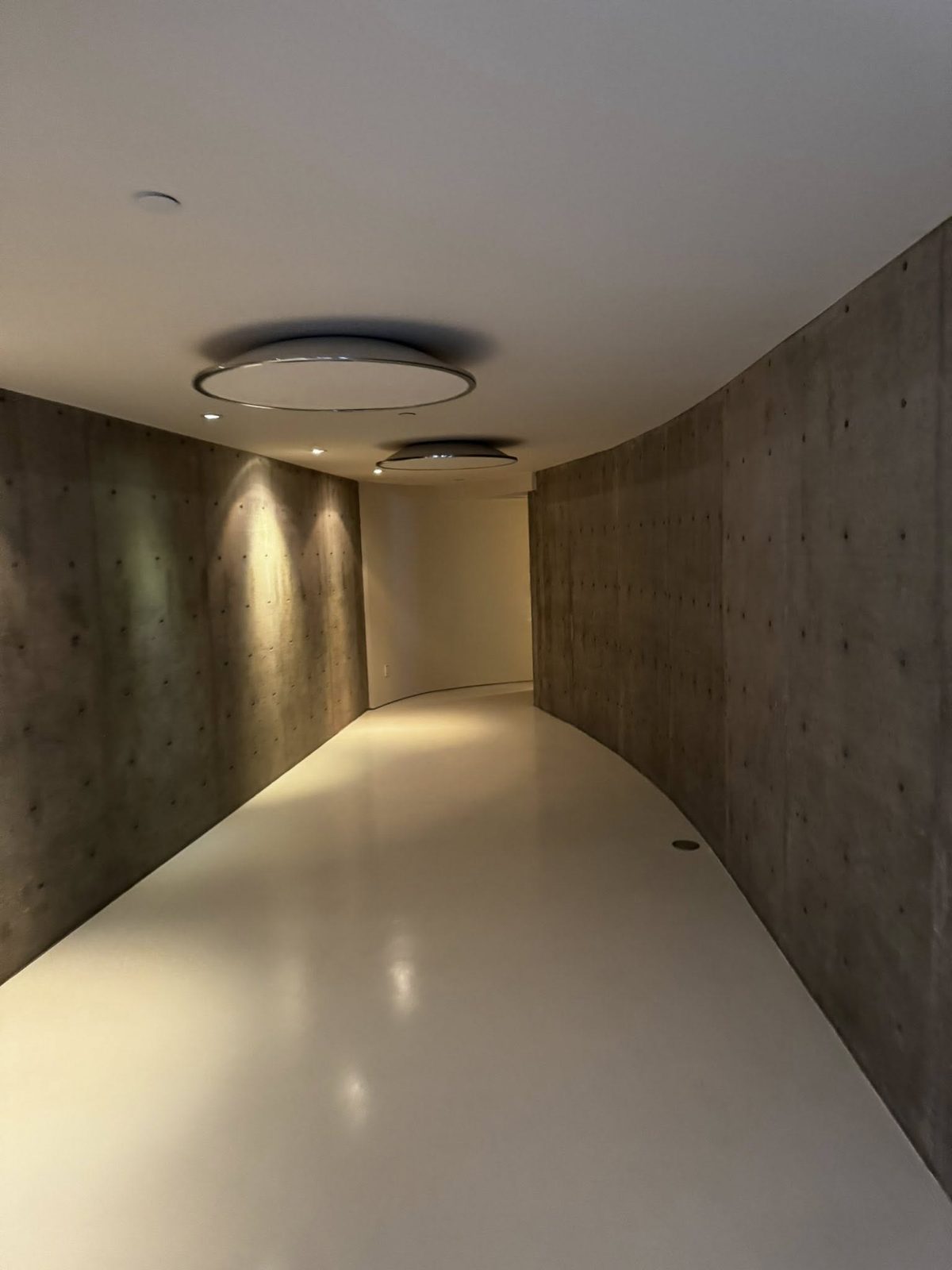 Finished curved board-formed concrete corridor with disc lighting in a Jericho Beach estate