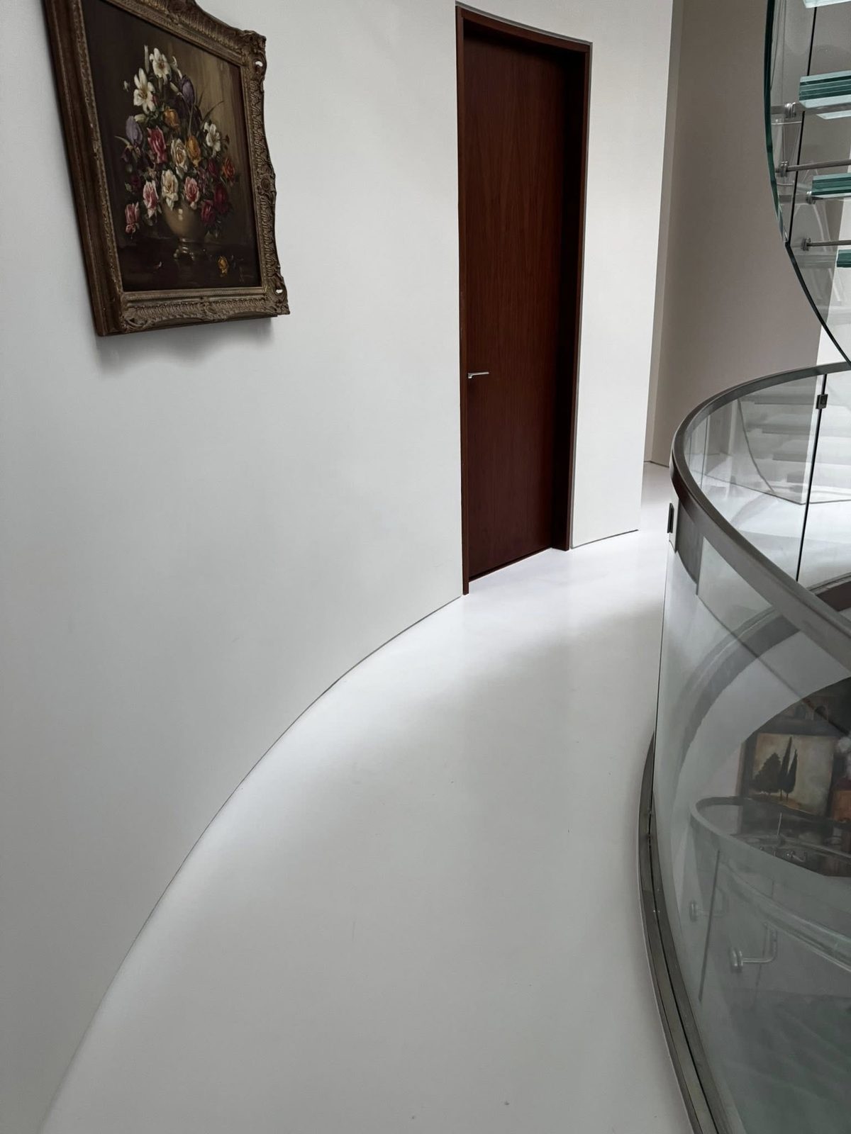 Finished curved white hallway with glass spiral staircase railing in a luxury Vancouver home