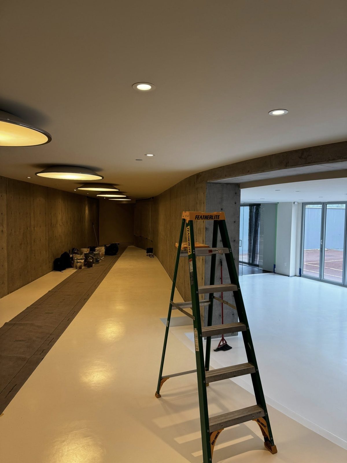 Curved board-formed concrete hallway with disc lighting in a high-end Vancouver estate