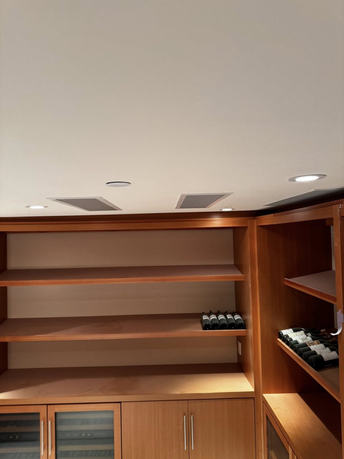 Wine room with built-in wood shelving and freshly painted ceiling in a luxury Vancouver home