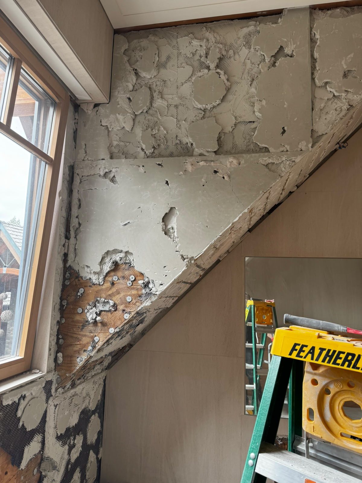 Tile removed to expose mortar bed and cement board on an angled wall during Whistler chalet demolition