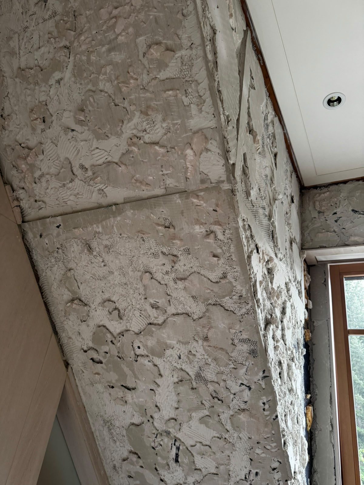 Close-up of demolished tile mortar bed over the angled wall surface in a Whistler chalet