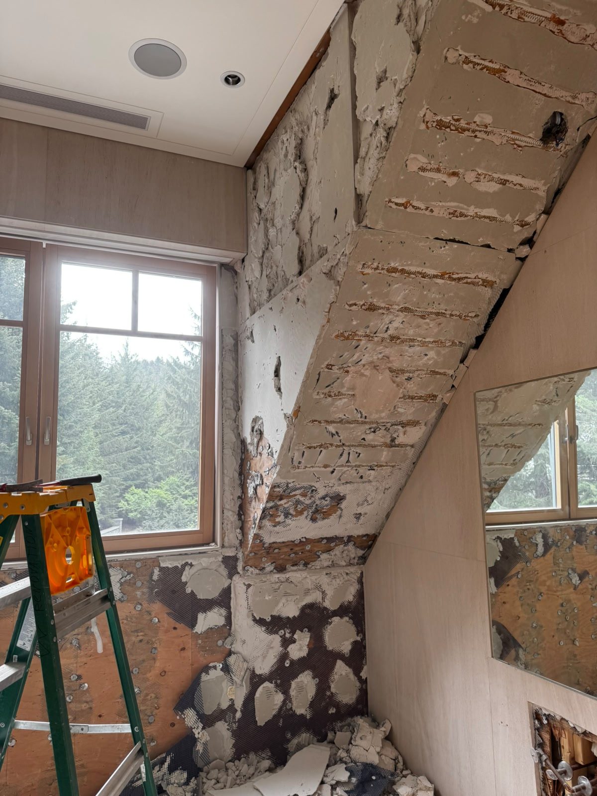 Demolition stage with tile and marble removed exposing substrate on the sloped shower zone of a Whistler chalet