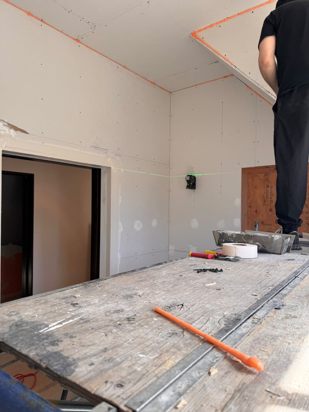 Drywall installation aligned with a green laser level across the angled walls of a Whistler renovation