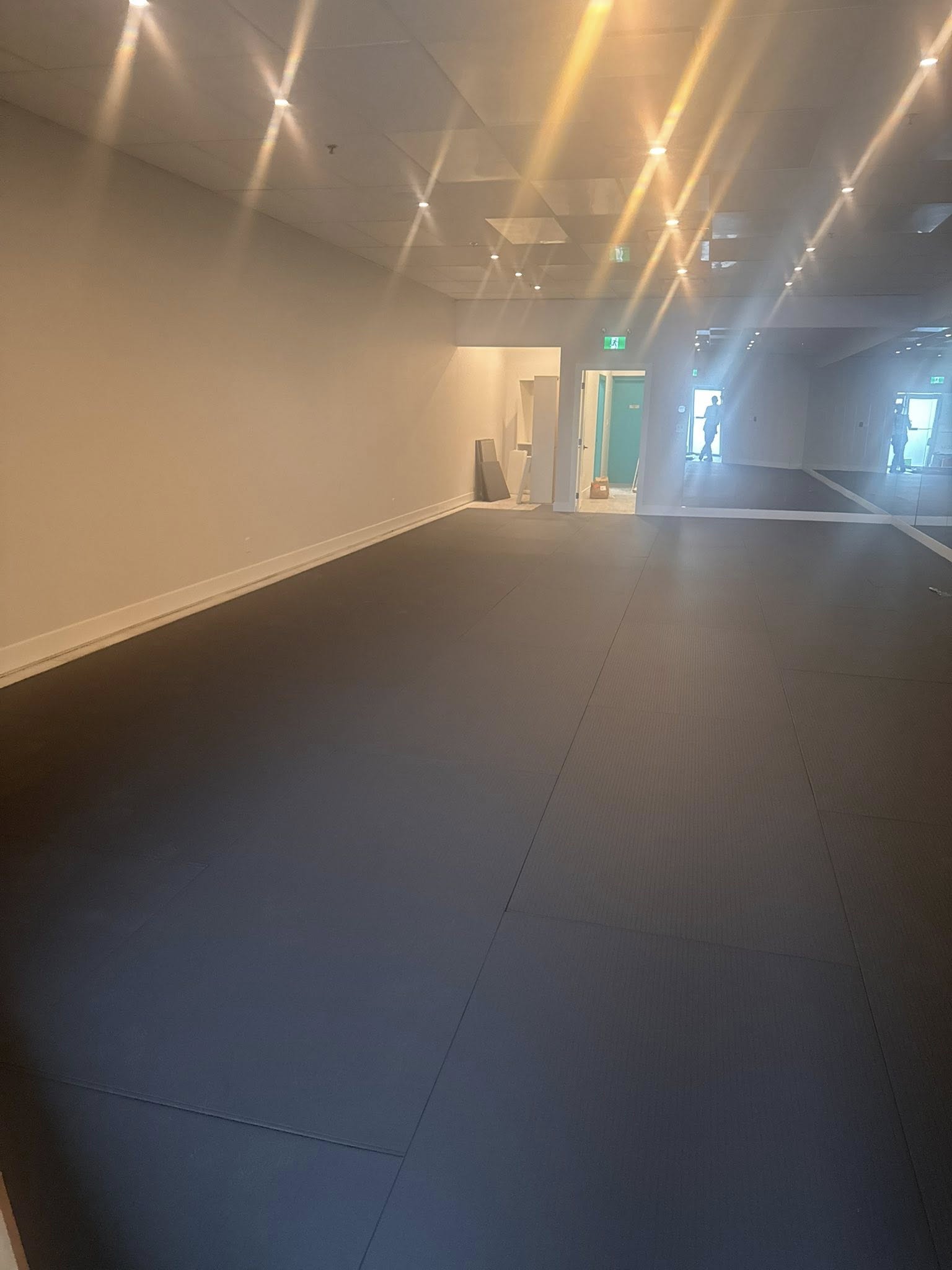 Finished yoga studio floor with black mats and mirror wall installed, Langley renovation