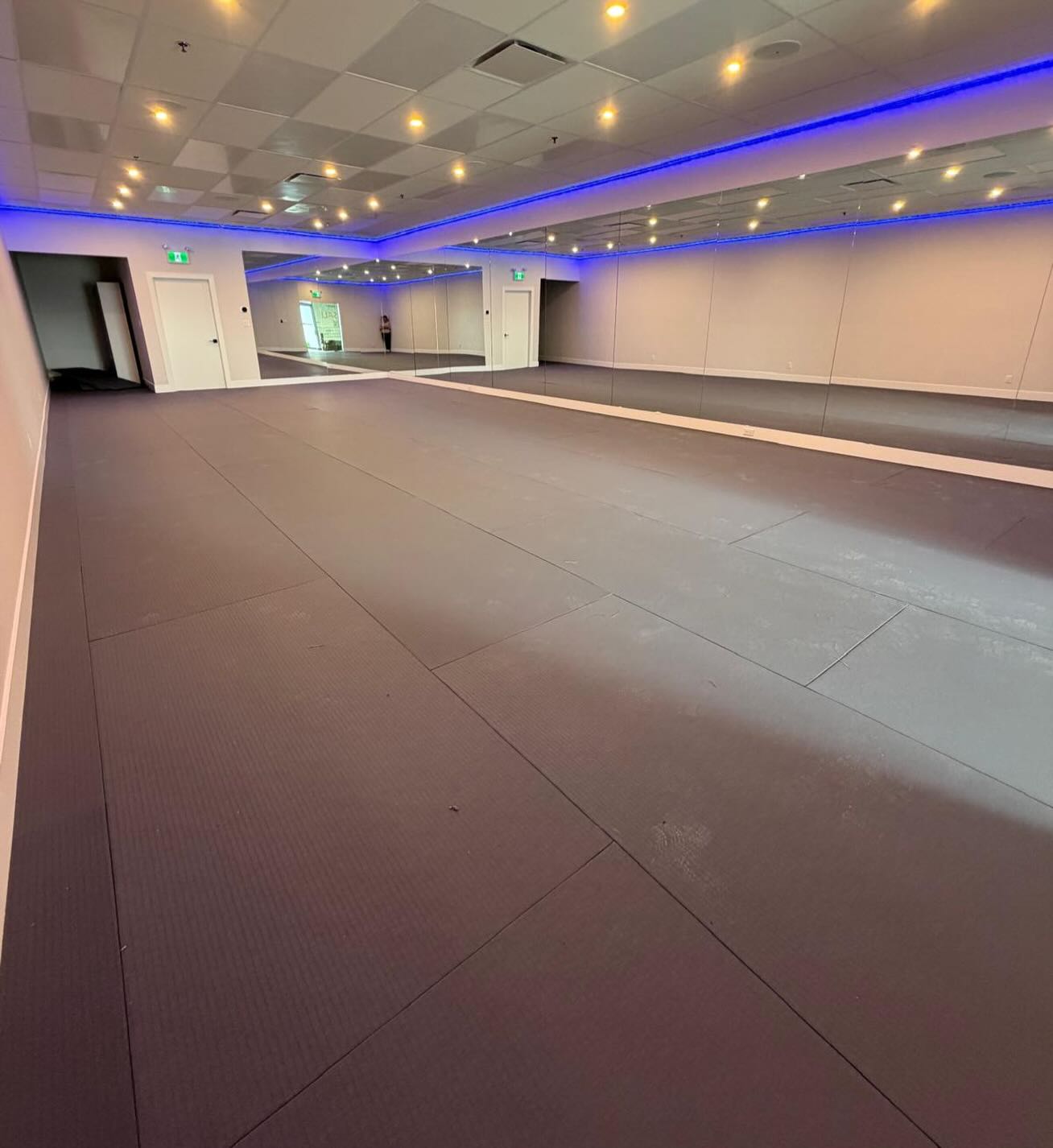 Finished yoga studio interior with mats, mirror wall and blue accent lighting, Langley BC